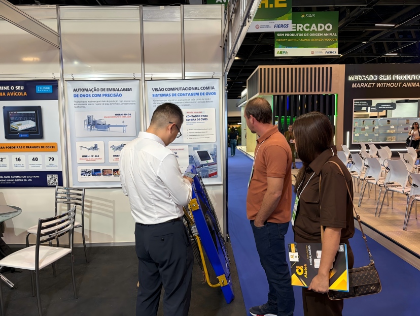 Visitors discussing an AI vision egg counter for layer farms at SIAVS 2026 Brazil